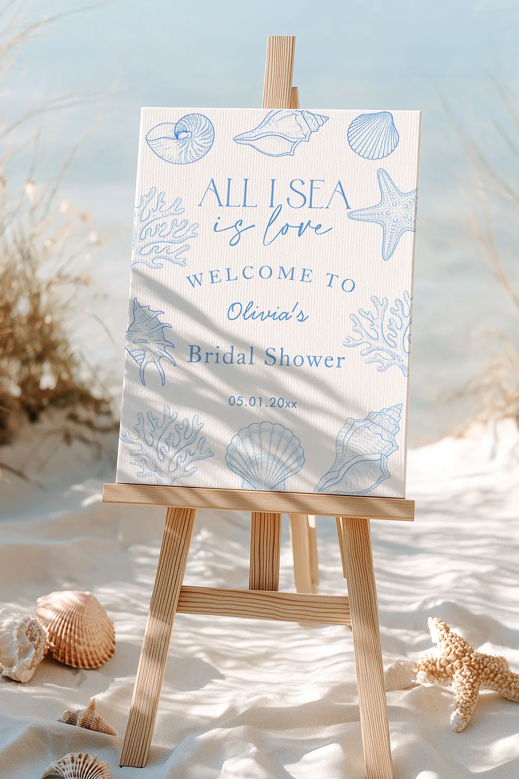 Coastal bridal shower welcome sign on an easel with seashells and a hydrangea stem