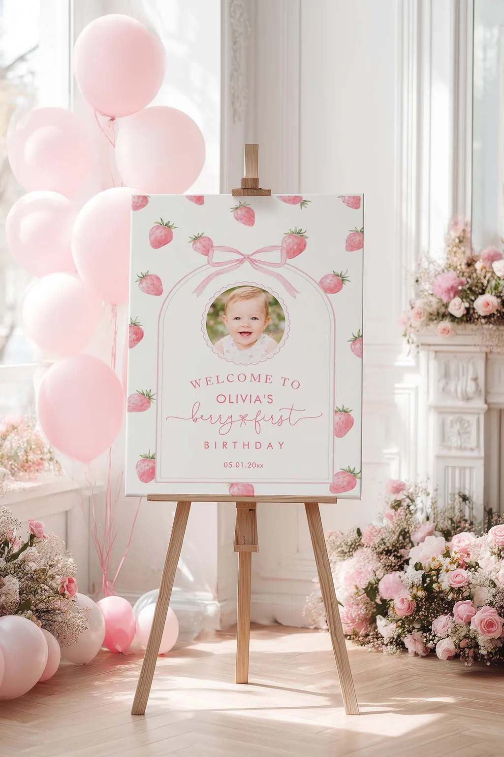 Strawberry first birthday welcome sign on an easel by the door with a few strawberries beside it