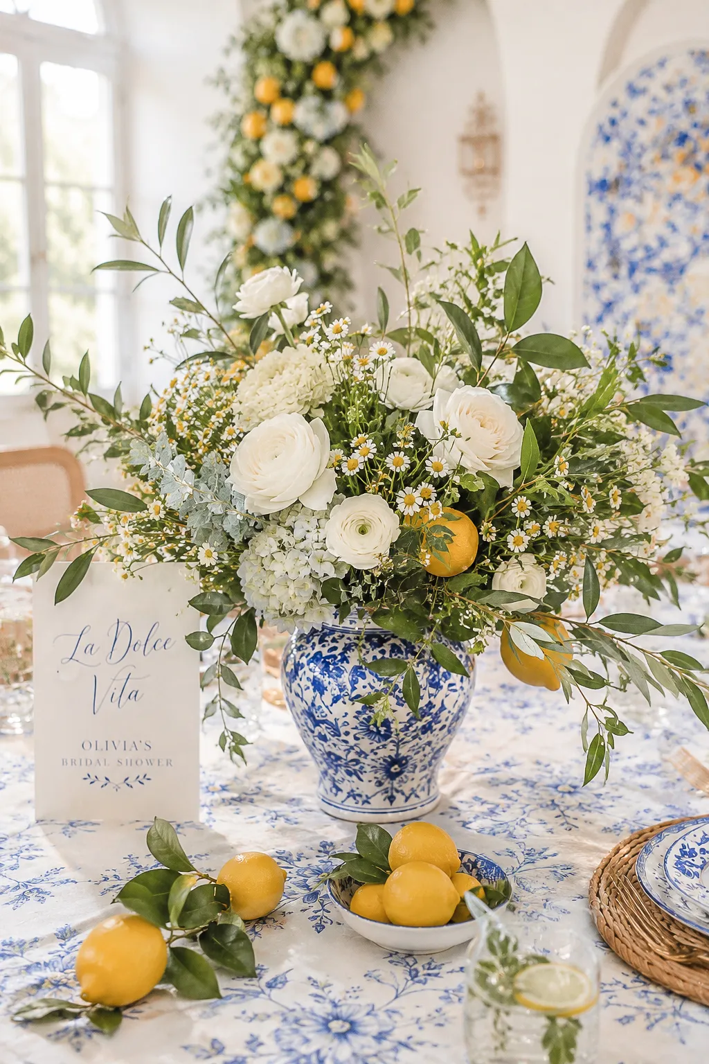 La Dolce Vita bridal shower flowers — white blooms, lemon branches and greenery in blue and white vases